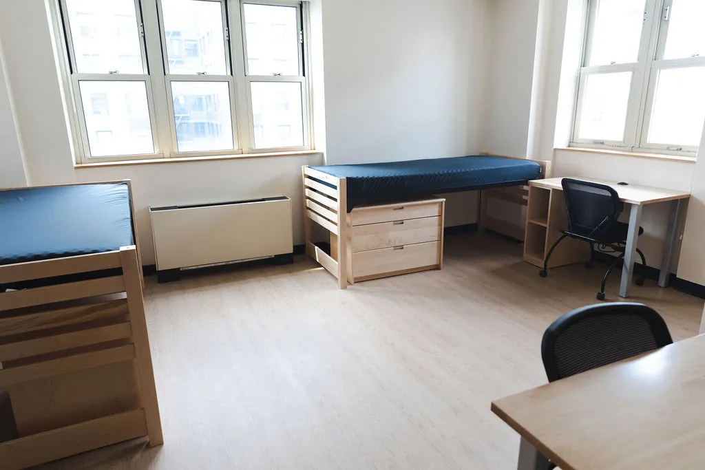 A double room dorm room with new flooring and furniture.