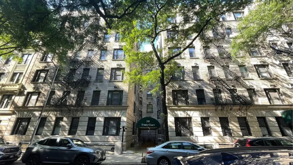 A view of 518 W. 111th Street from across the street, a six floor apartment building with a green canopy over the entrance.