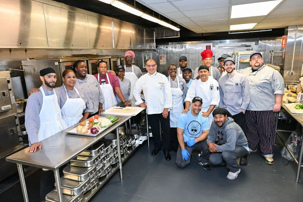 John Jay Dining Hall employees gather around the kitchen with Culinary Institute of America training instructor, Chefs Phil Crispo. 