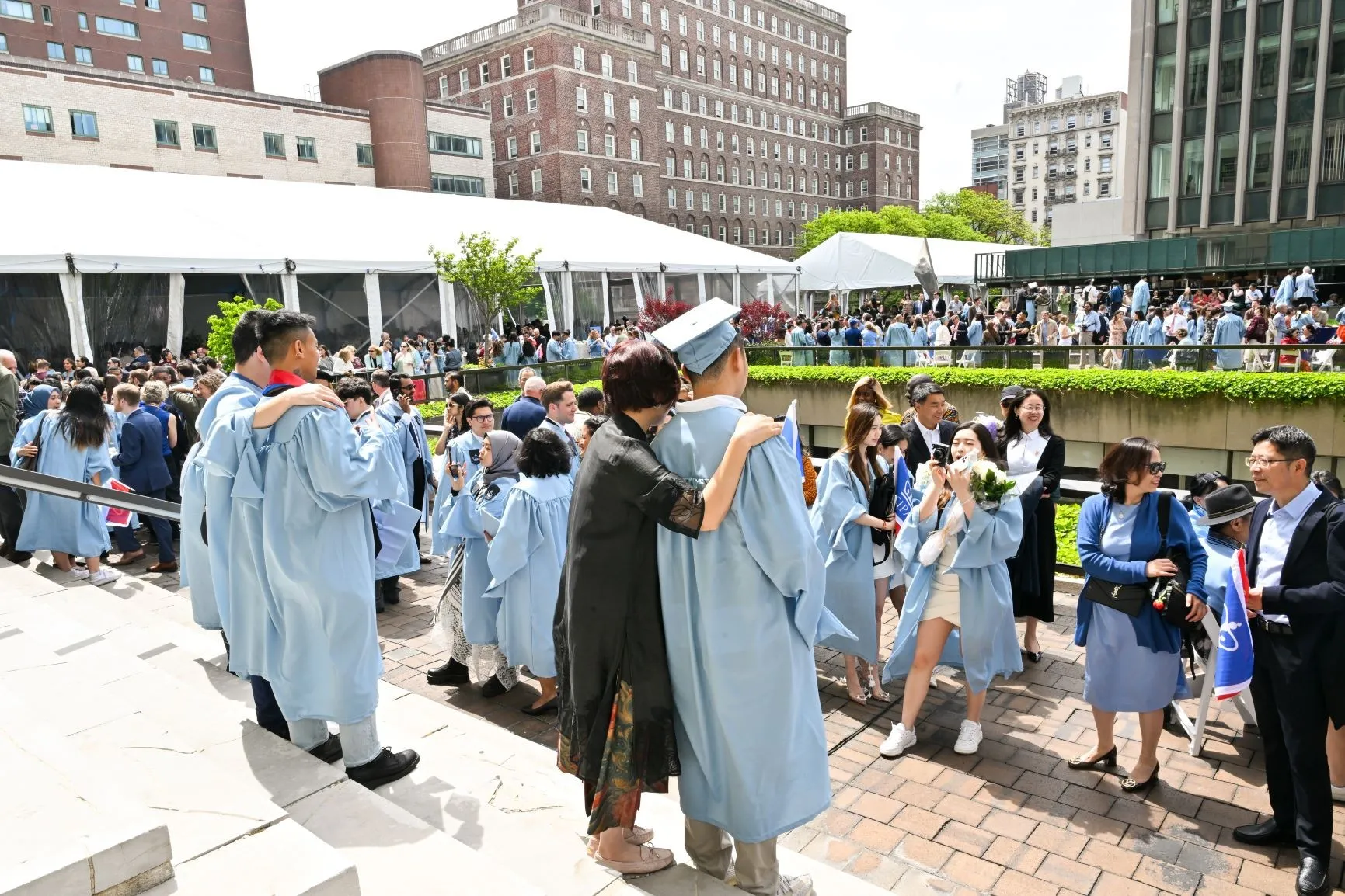 Graduates gather on steps of the International Affairs Building and other people take photos of them.