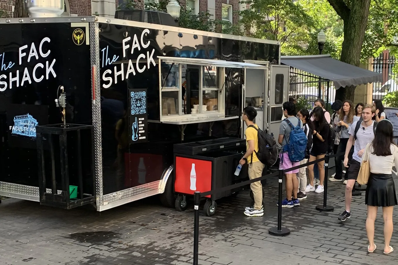 People line up at a black food truck that is parked in Wien Courtyard that says "The Fac Shack."