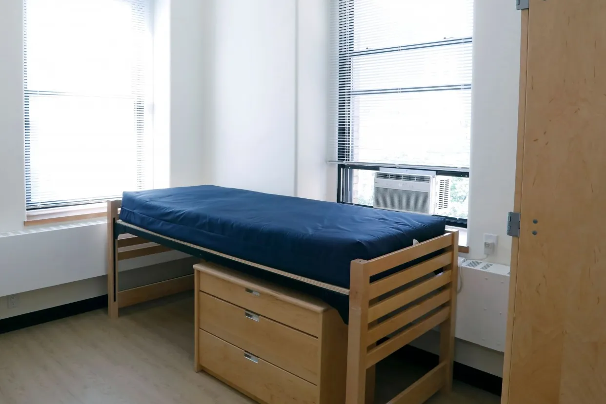 A dorm room that has been refreshed with new flooring, lighting, paint, and furniture.