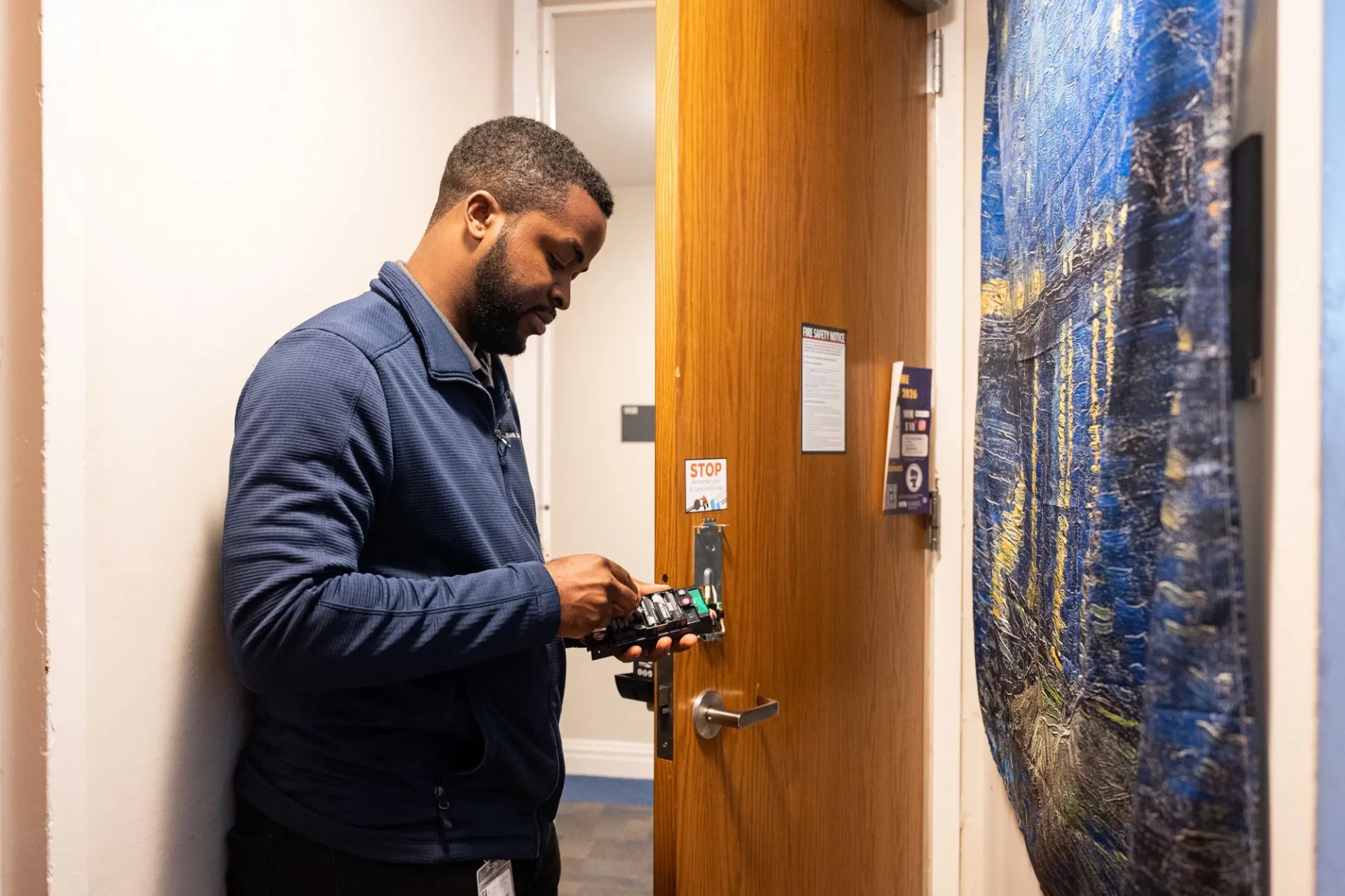 A person installs an electronic lock in a dorm room door.