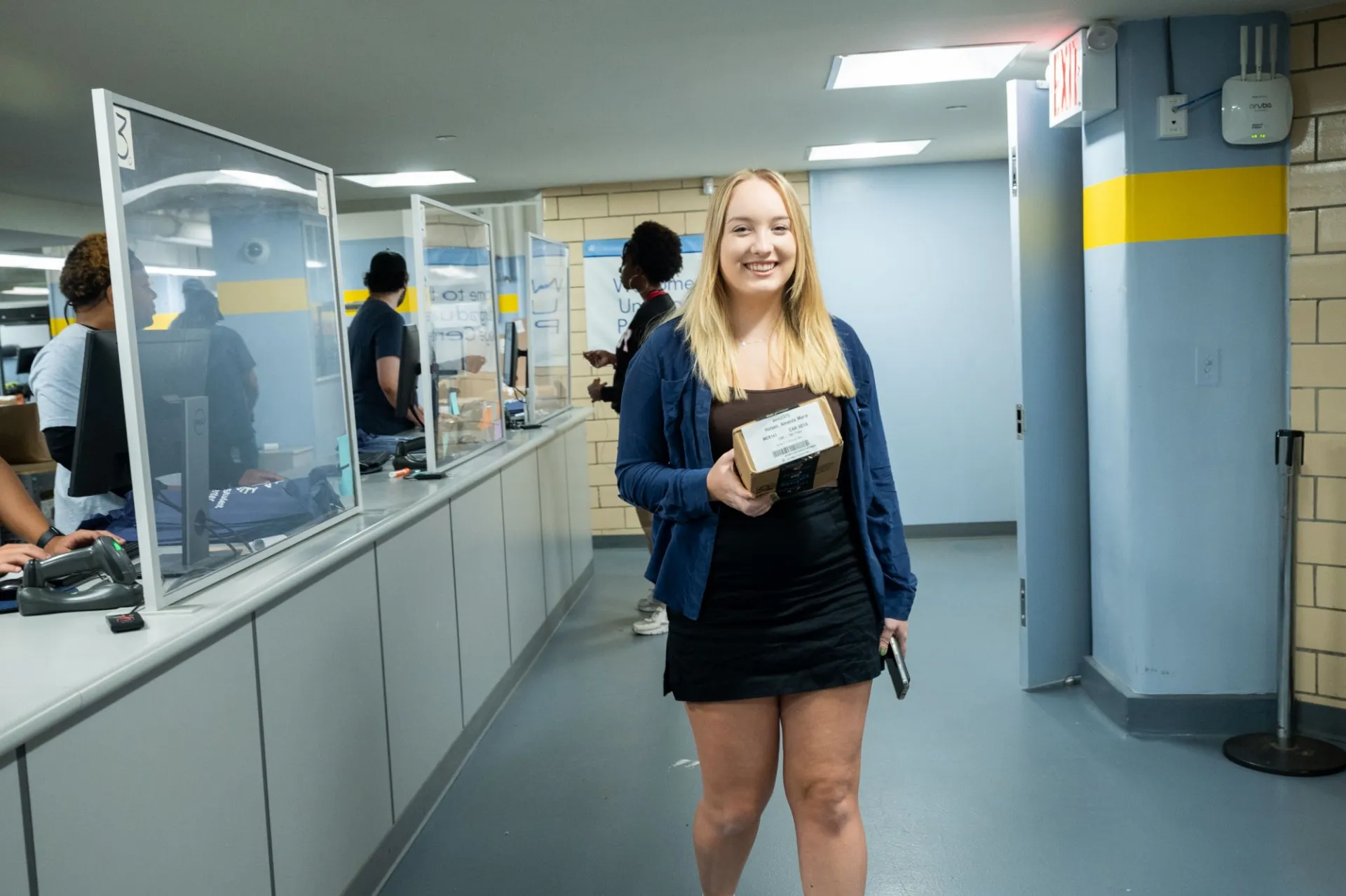 A student walks away from the Student Mail center holding a package.