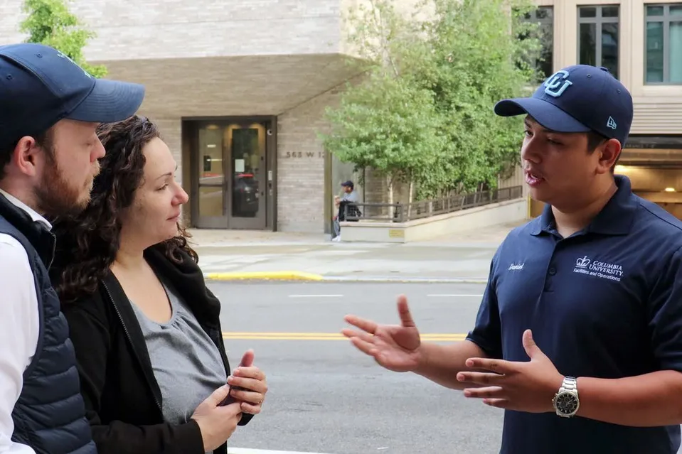 A Columbia Residential employee speaks to two people on the street.