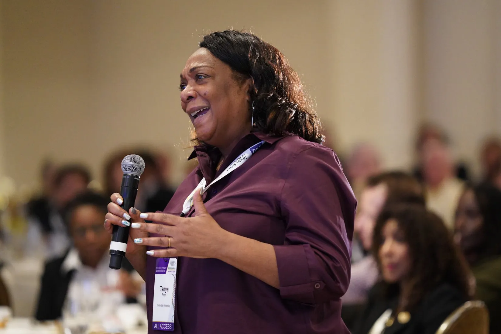 Tanya Pope stands up to ask a question at the middle of a conference.