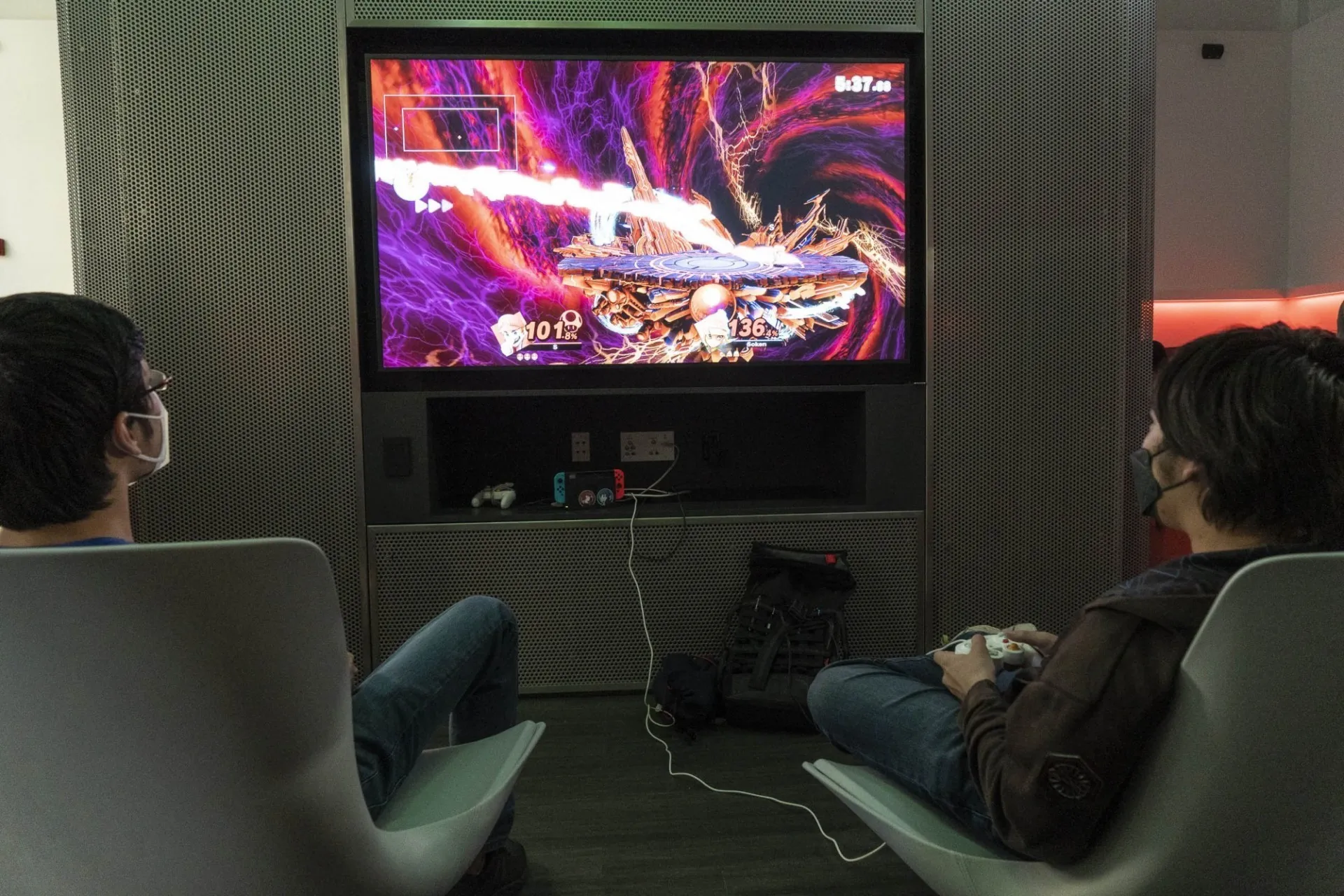 Students sitting in gaming chairs with headphones on playing a game